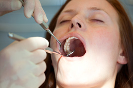 A woman having her teeth cleaned by a hygienist 